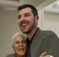 Bruno Vassari rindo, abraçado a uma moradora